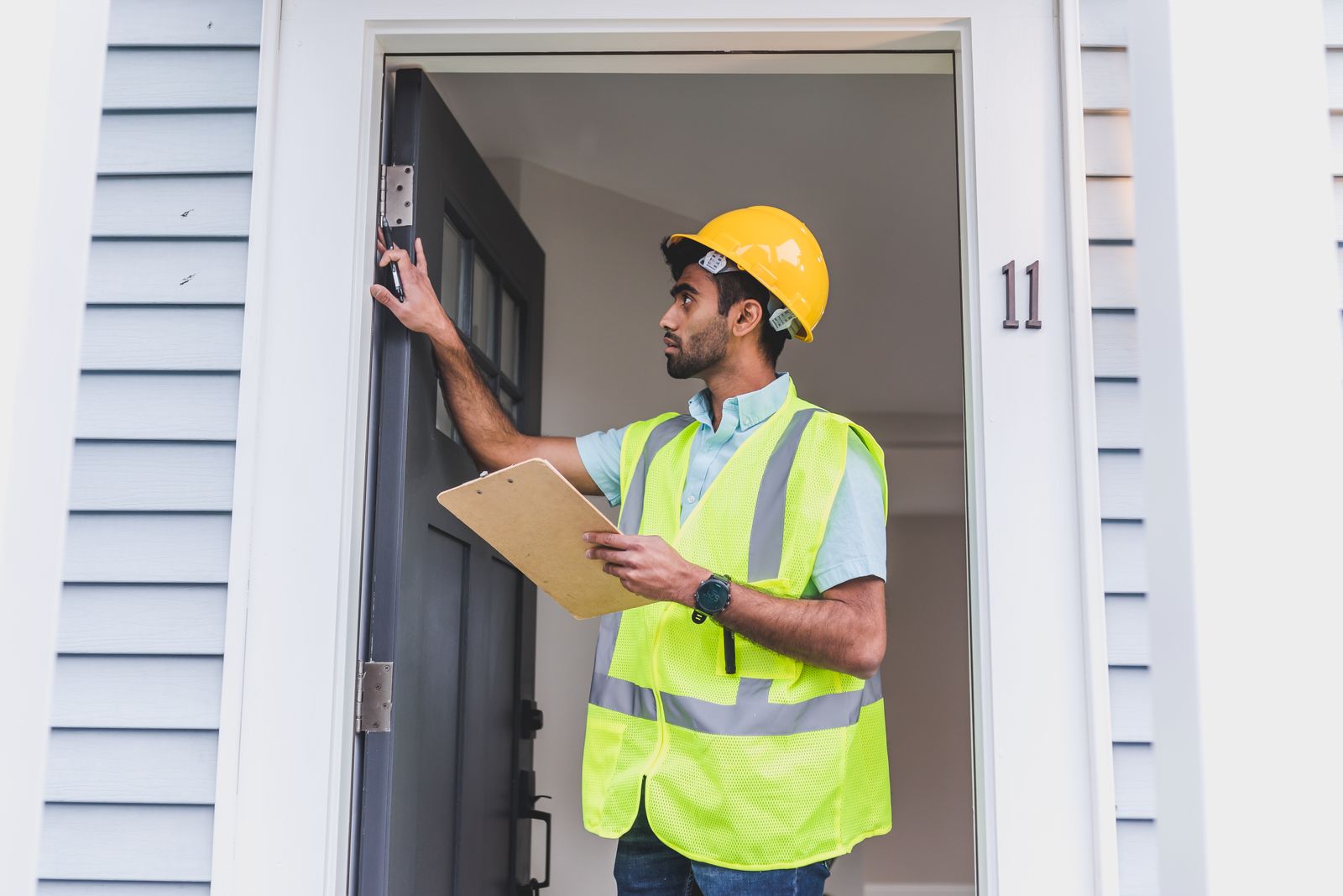 A licensed Service Tech in a hard hat and safety vest arriving at a home front door